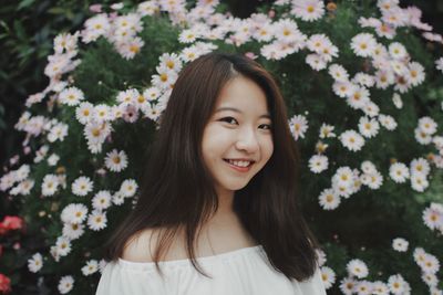 Portrait of smiling young woman by plants at public park