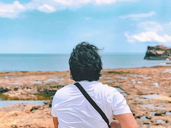 Rear view of woman looking at sea shore against sky