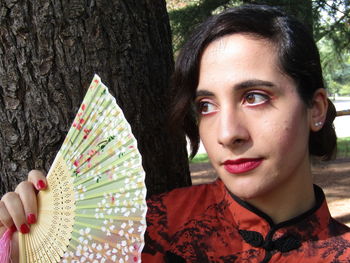 Portrait of woman against tree trunk