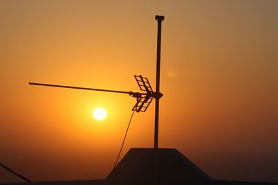 Low angle view of silhouette windmill against orange sky