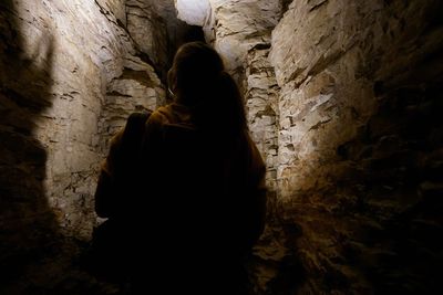 Rear view of woman standing on rock against wall