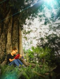 Surface level shot of woman writing diary while sitting on grassy field at park