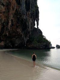 Full length of man on rock at beach against sky