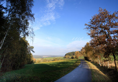 Road amidst green landscape against blue sky