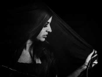 Close-up of woman wearing dupatta against black background