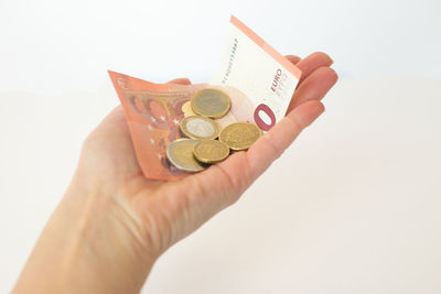 Close-up of hand holding coin against white background