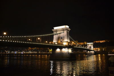 Illuminated bridge over river at night