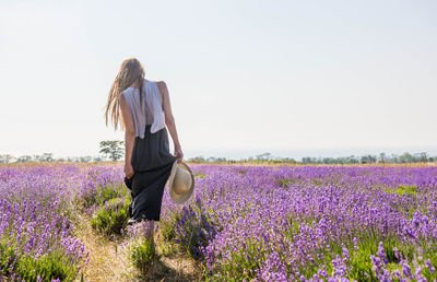 Rear view of woman with umbrella on field against sky