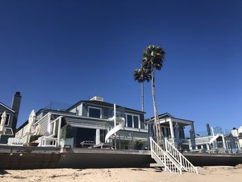 Low angle view of palm trees on beach against clear blue sky