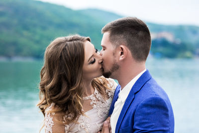 Couple kissing against lake