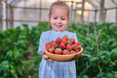 Portrait of cute girl holding strawberries