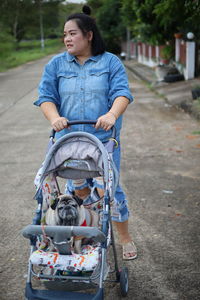 Woman with dog sitting in baby stroller on road
