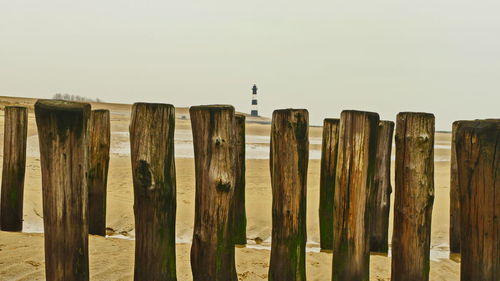 Wooden posts on fence against clear sky