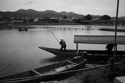 Man fishing in lake against sky