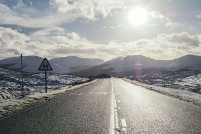 A winding road warning sign on an icy road in a snowy winter mountain scene in scotland