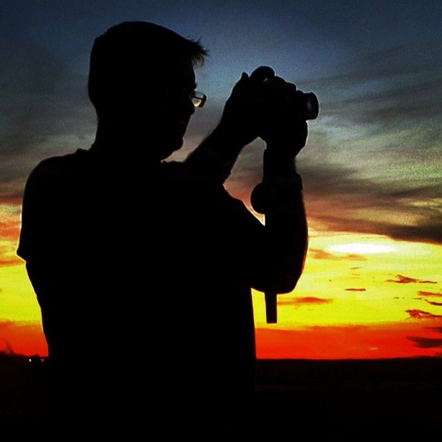 silhouette, sunset, lifestyles, sky, leisure activity, standing, men, orange color, three quarter length, full length, outline, person, togetherness, side view, cloud - sky, bonding, rear view