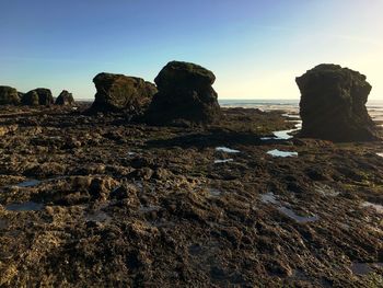 Rock formation on beach against clear sky