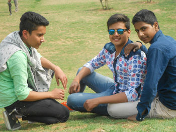 Happy friends sitting on grassland