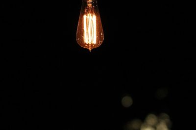 Close-up of illuminated light bulb against black background