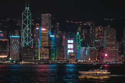 Illuminated buildings by river at night