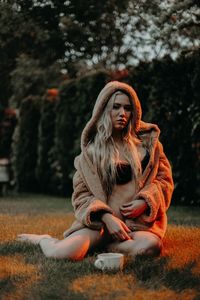 Portrait of young woman sitting on tree