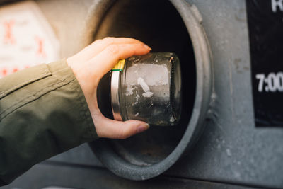 Cropped hand throwing jar in garbage bin