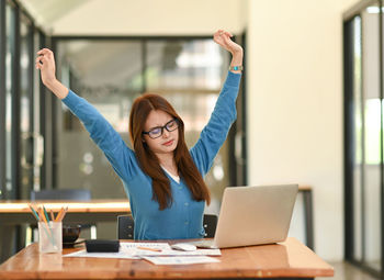 Young woman using laptop while sitting on table
