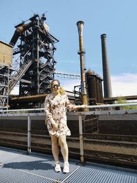 Full length of woman standing on metal structure against sky