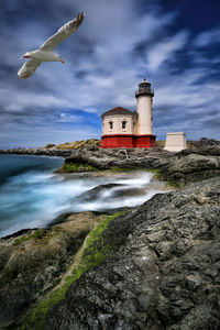 Lighthouse by sea against sky