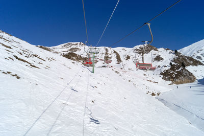 Scenic view of snowcapped mountains against clear sky chair lift in the foreground