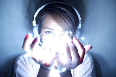 Portrait of young woman holding illuminated light