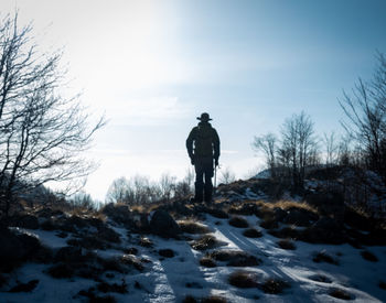 Rear view of man standing on snow covered field