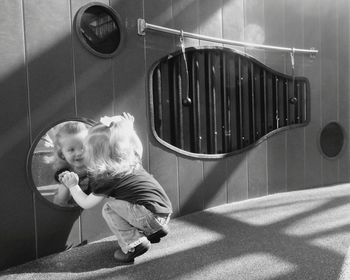 Curious little girl looking in mirror at playground