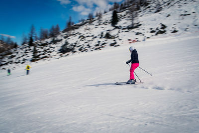 Woman skiing on snowcapped mountain against sky