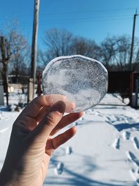 Close-up of hand holding ice cream against sky