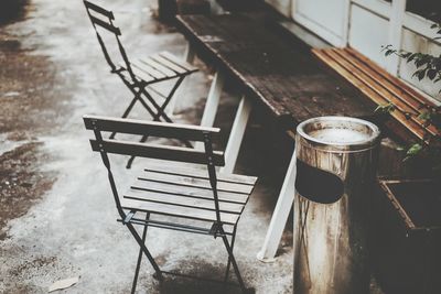 High angle view of chairs and bench by garbage can at park