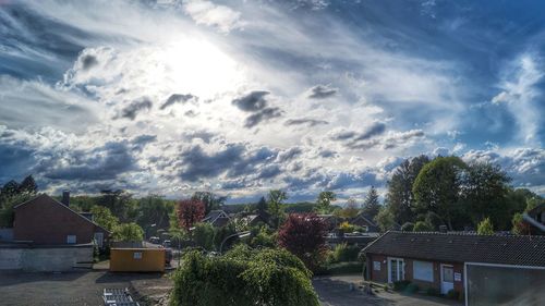 Trees and houses against sky in city