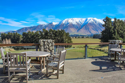 Empty chairs and table against mountains