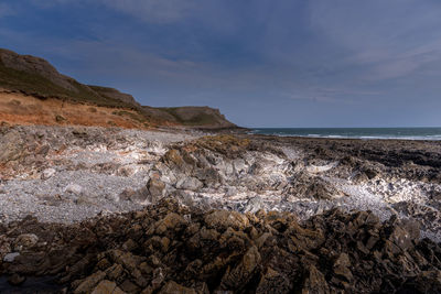 Scenic view of rocks on beach against sky