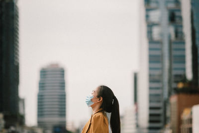 Side view of businesswoman wearing mask standing outdoors
