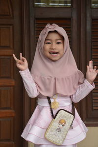 Portrait of a smiling girl standing against the wall