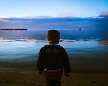 Rear view of man looking at sea against sky