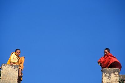 Low angle view of man standing against blue sky