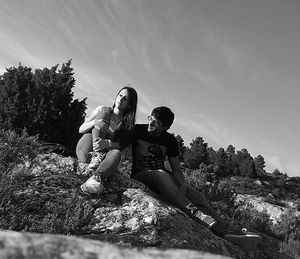 People on rock against sky