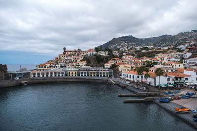 Bridge over river by buildings in city against sky