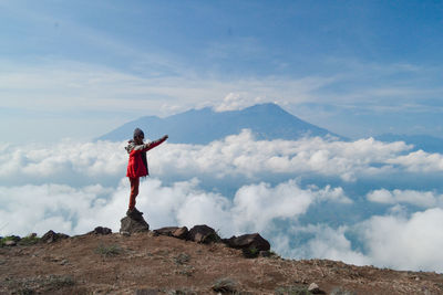 Woman standing on rock at mountain against sky