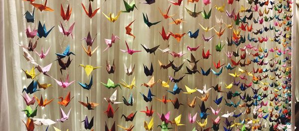 Full frame shot of colorful paper cranes hanging against curtain