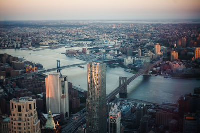 High angle view of buildings by river against sky in city