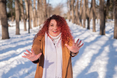 Portrait of smiling young woman standing on snow covered field