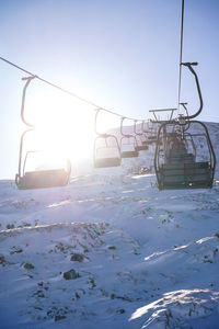 Ski lift over snow covered landscape against sky